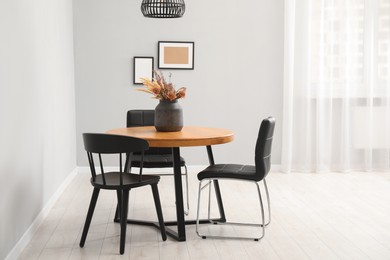 Photo of Wooden table with black chairs in stylish dining room