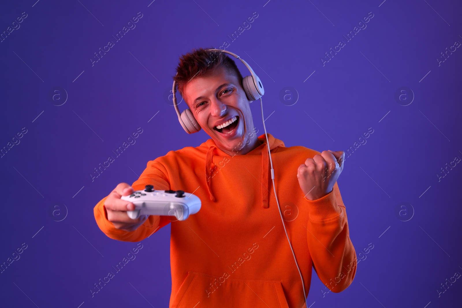 Photo of Happy young man with controller on violet background