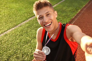 Photo of Happy winner with silver medal taking selfie at stadium. Space for text