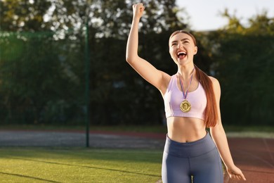 Photo of Happy winner with golden medal at stadium. Space for text