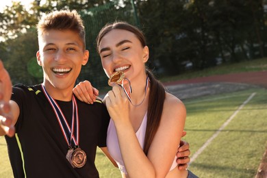 Portrait of happy winners with medals at stadium. Space for text