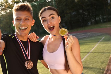 Portrait of happy winners with medals at stadium. Space for text