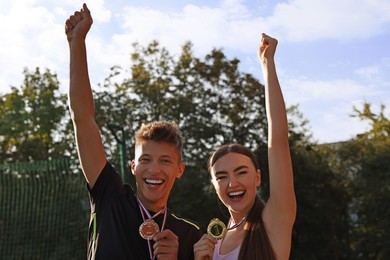 Portrait of happy winners with medals outdoors