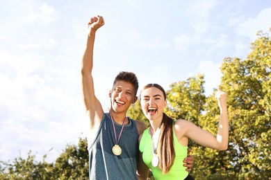 Happy winners with medals outdoors on sunny day