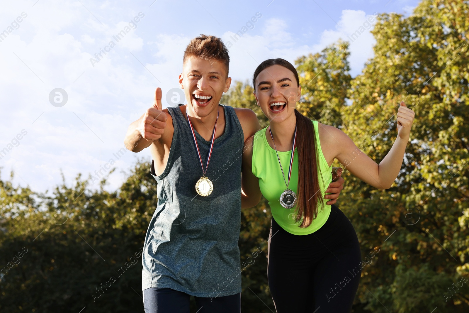 Photo of Happy winners with medals outdoors on sunny day