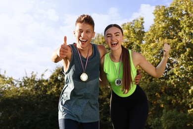 Happy winners with medals outdoors on sunny day