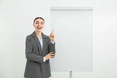 Happy woman near flip chart on white background. Mockup for design