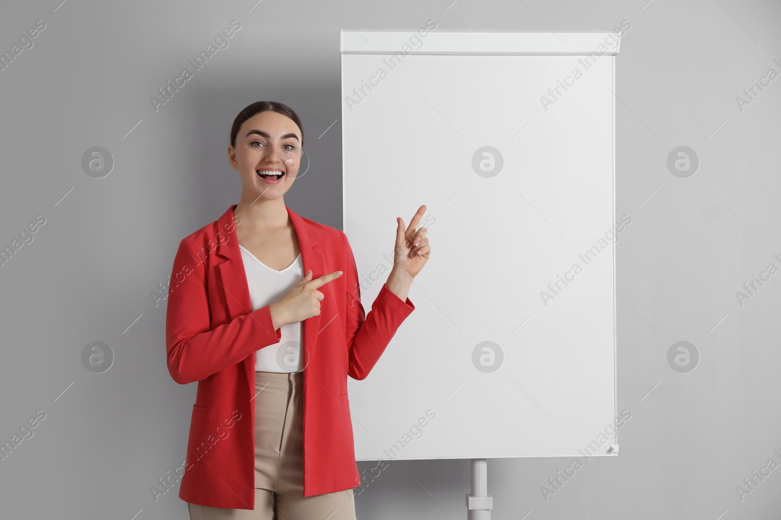 Photo of Happy woman near flip chart on grey background. Mockup for design