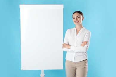 Photo of Happy woman near flip chart on light blue background. Mockup for design