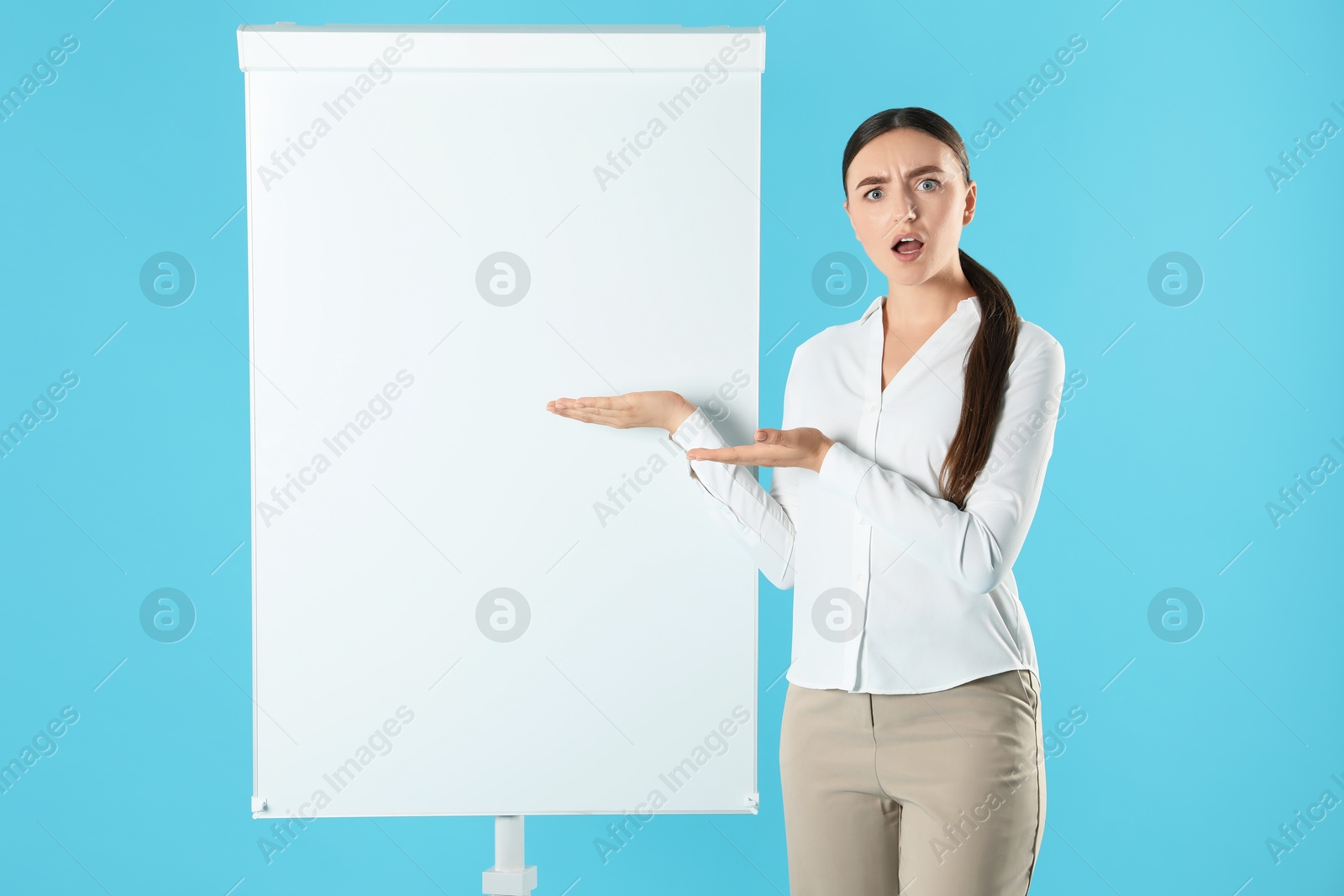 Photo of Confused woman near flip chart on light blue background. Mockup for design