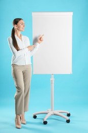 Happy woman near flip chart on light blue background. Mockup for design