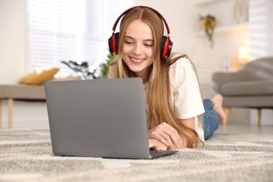 Photo of Teenage girl in headphones using laptop at home