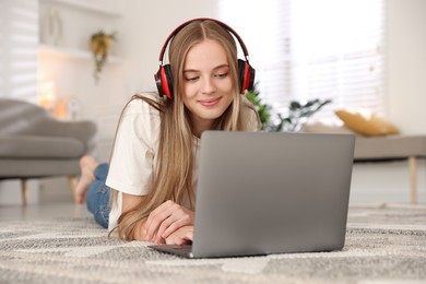 Teenage girl in headphones using laptop at home