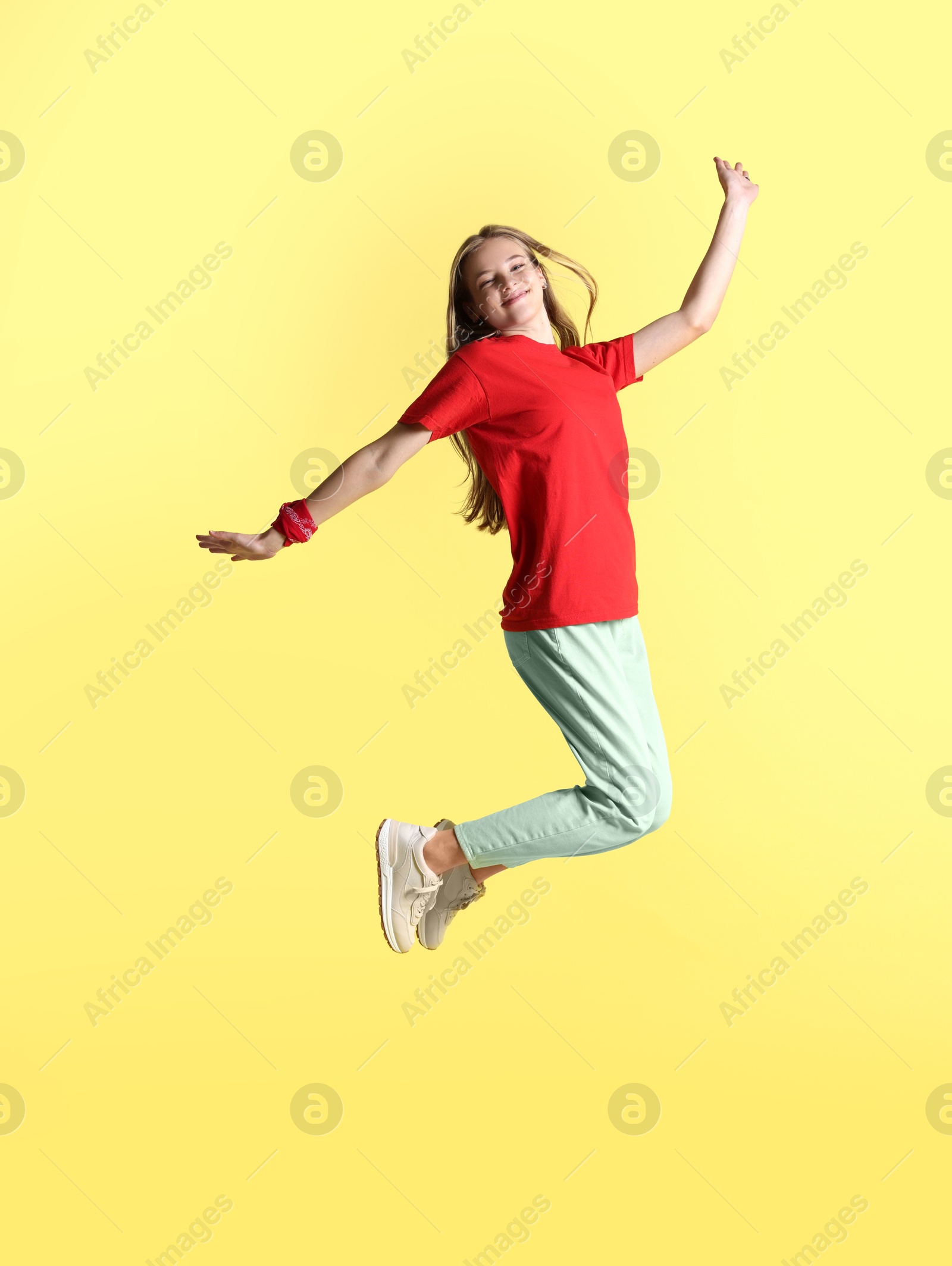 Photo of Happy teenage girl jumping on yellow background