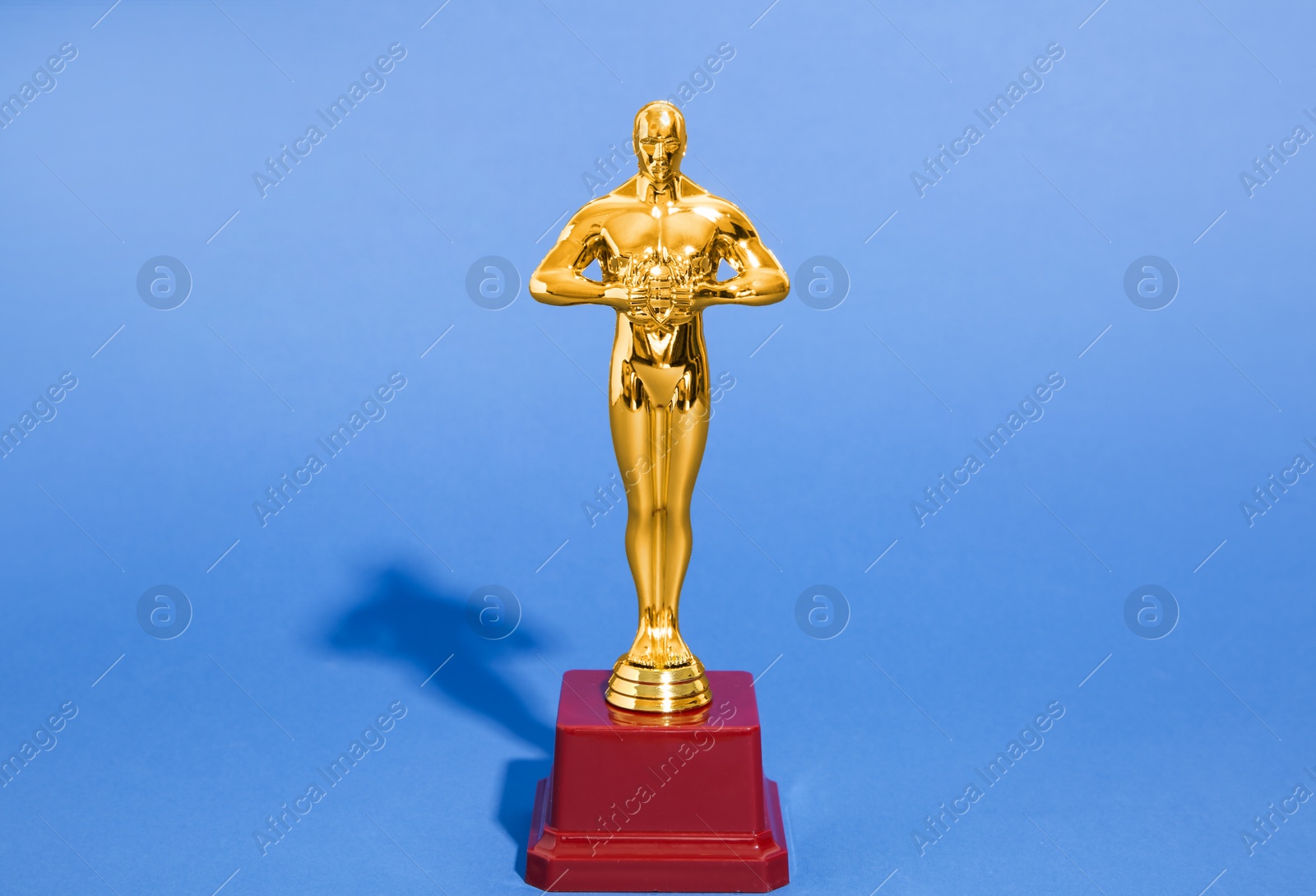 Photo of Golden trophy in shape of human figure on blue background