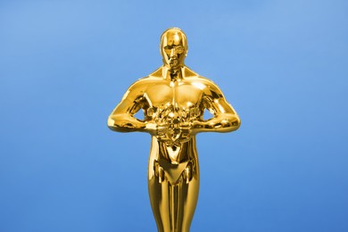 Photo of Golden trophy in shape of human figure on blue background, closeup