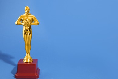 Golden trophy in shape of human figure on blue background, space for text