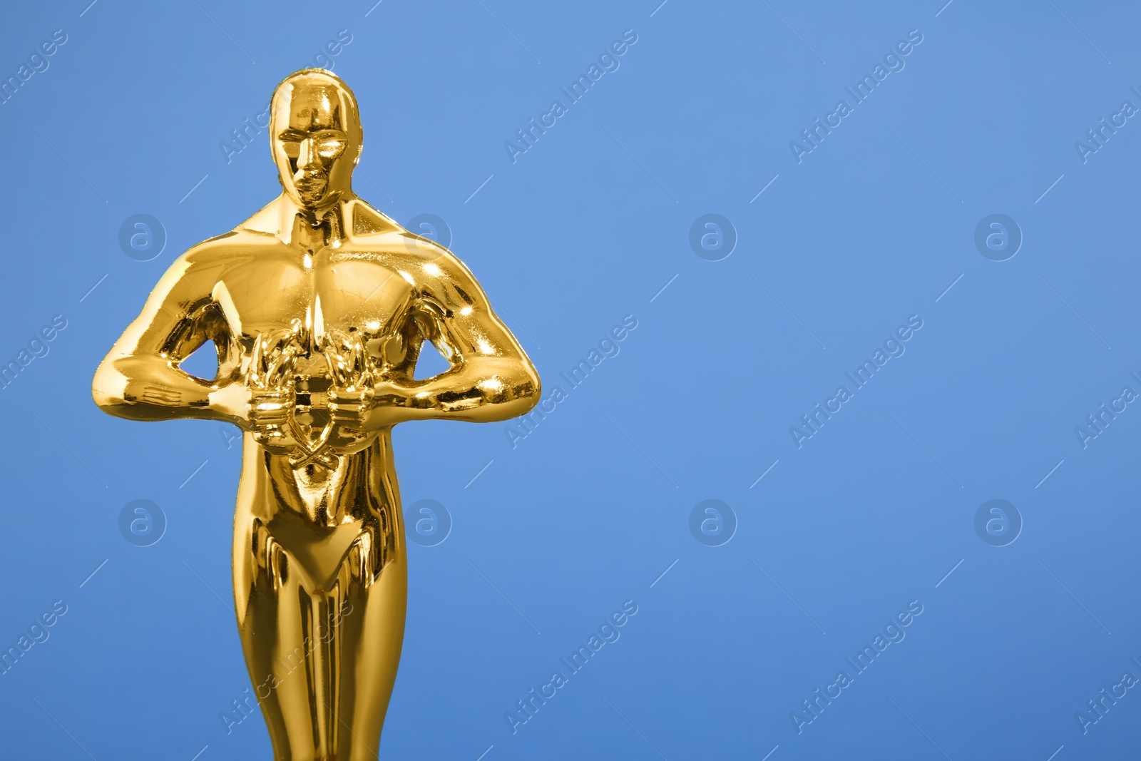 Photo of Golden trophy in shape of human figure on blue background, closeup. Space for text