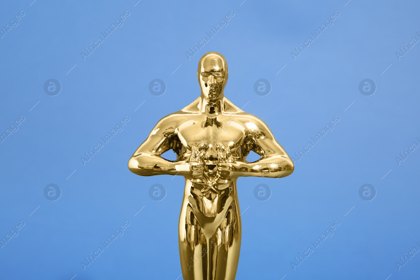 Photo of Golden trophy in shape of human figure on blue background, closeup