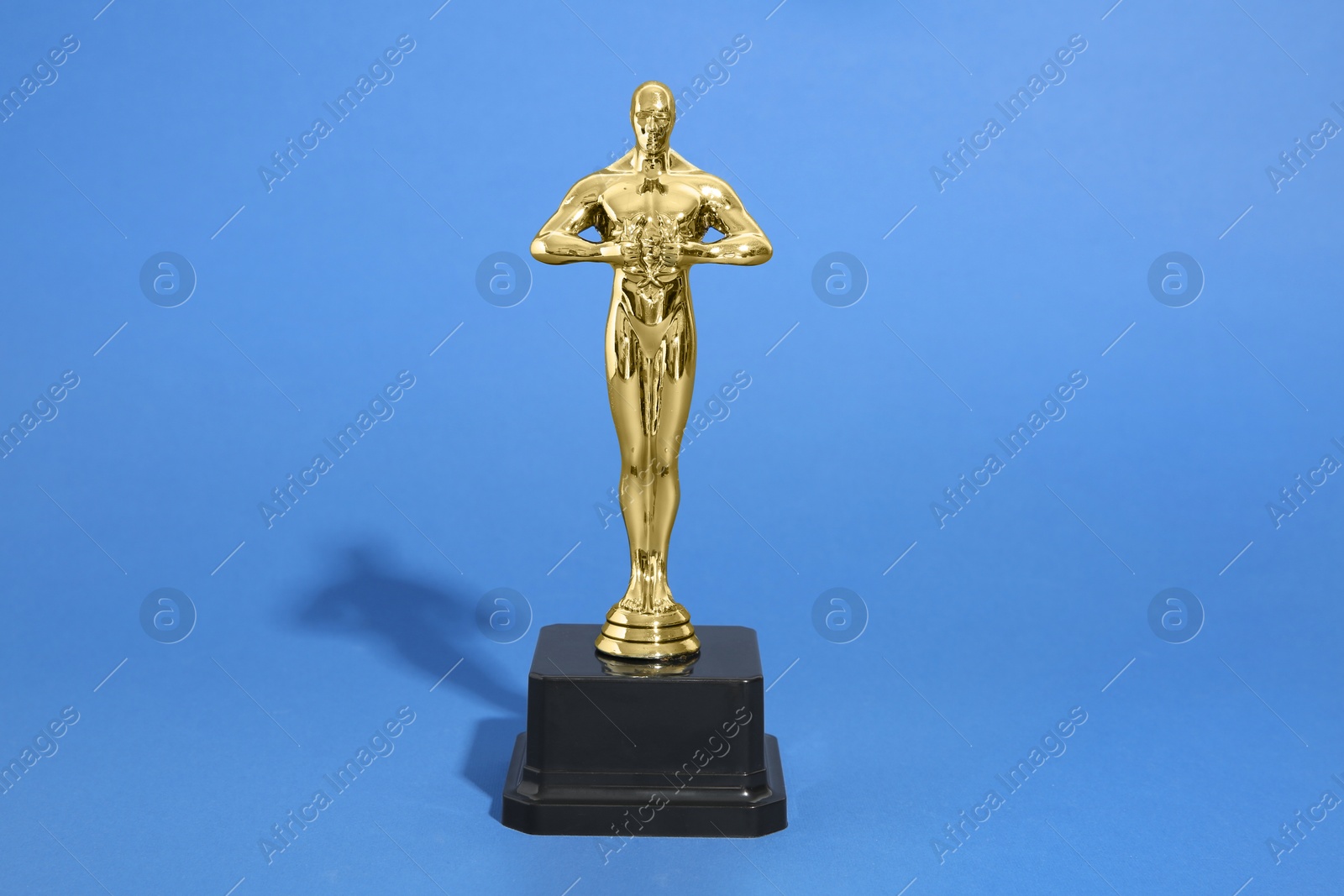 Photo of Golden trophy in shape of human figure on blue background