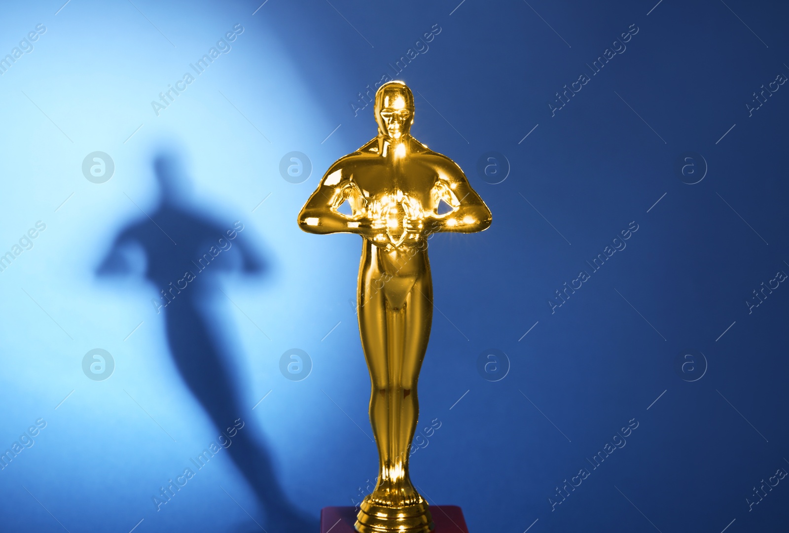 Photo of Golden trophy in shape of human figure on blue background