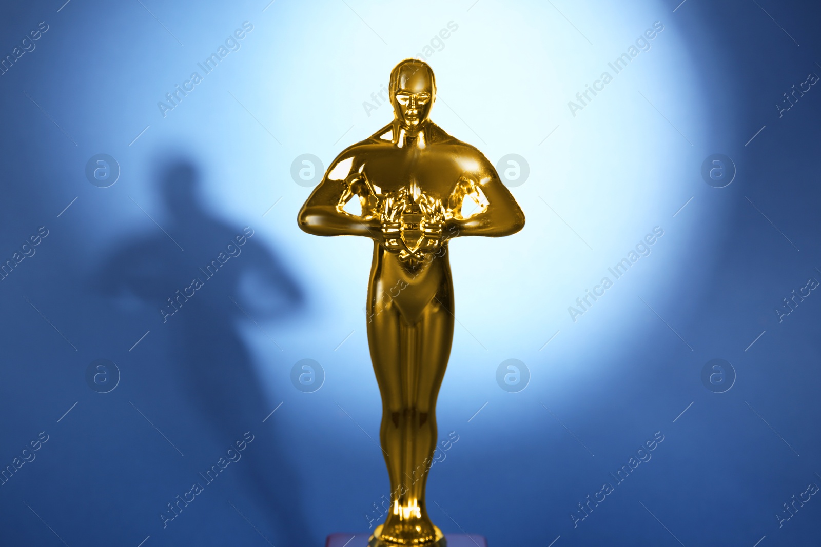 Photo of Golden trophy in shape of human figure on blue background