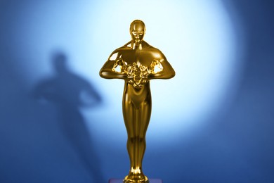 Photo of Golden trophy in shape of human figure on blue background