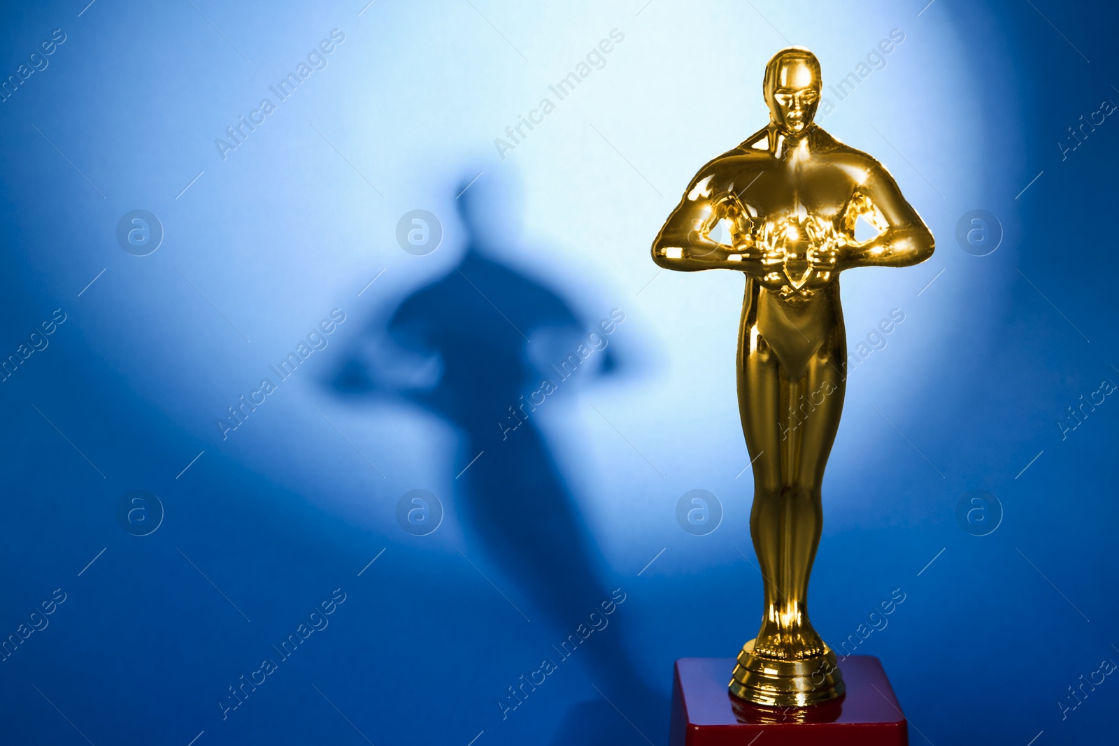 Photo of Golden trophy in shape of human figure on blue background, space for text