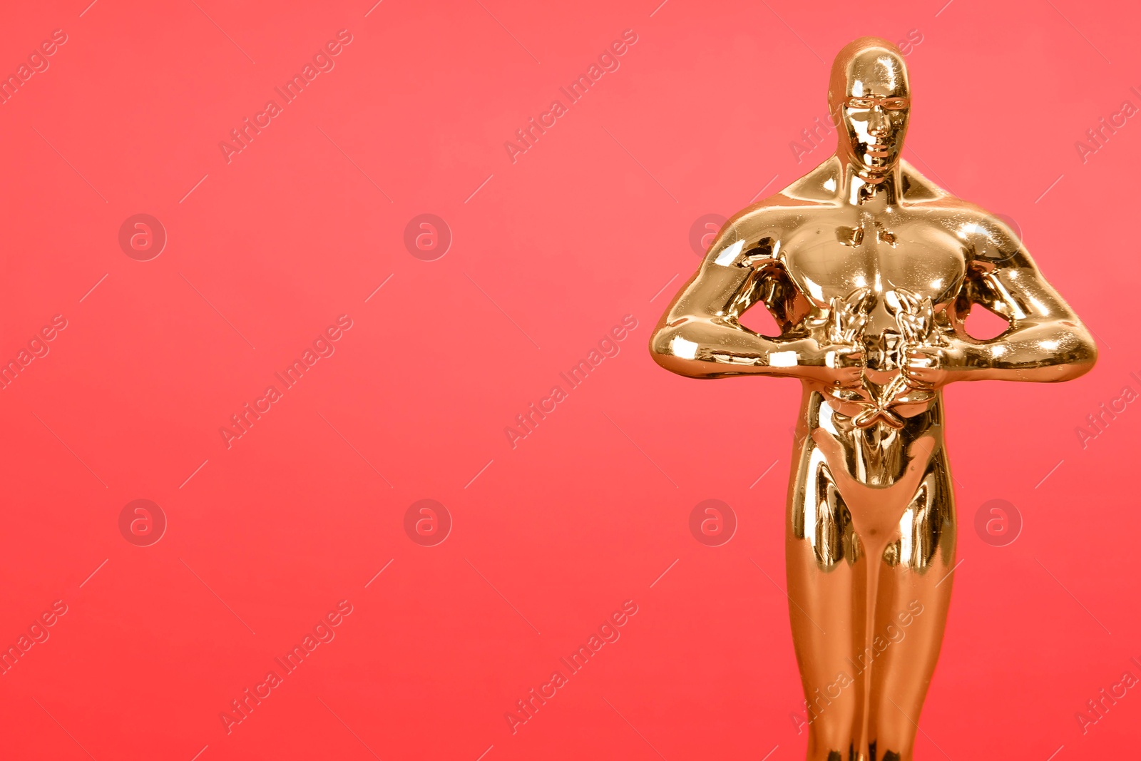 Photo of Golden trophy in shape of human figure on red background, closeup. Space for text