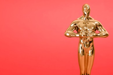 Photo of Golden trophy in shape of human figure on red background, closeup. Space for text