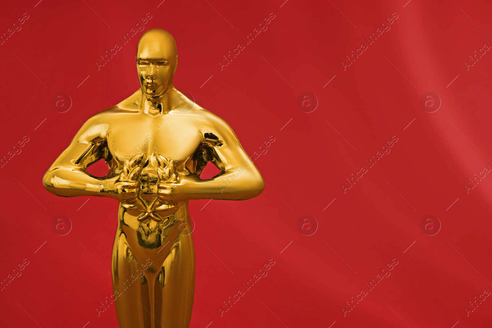 Photo of Golden trophy in shape of human figure on red background, closeup. Space for text