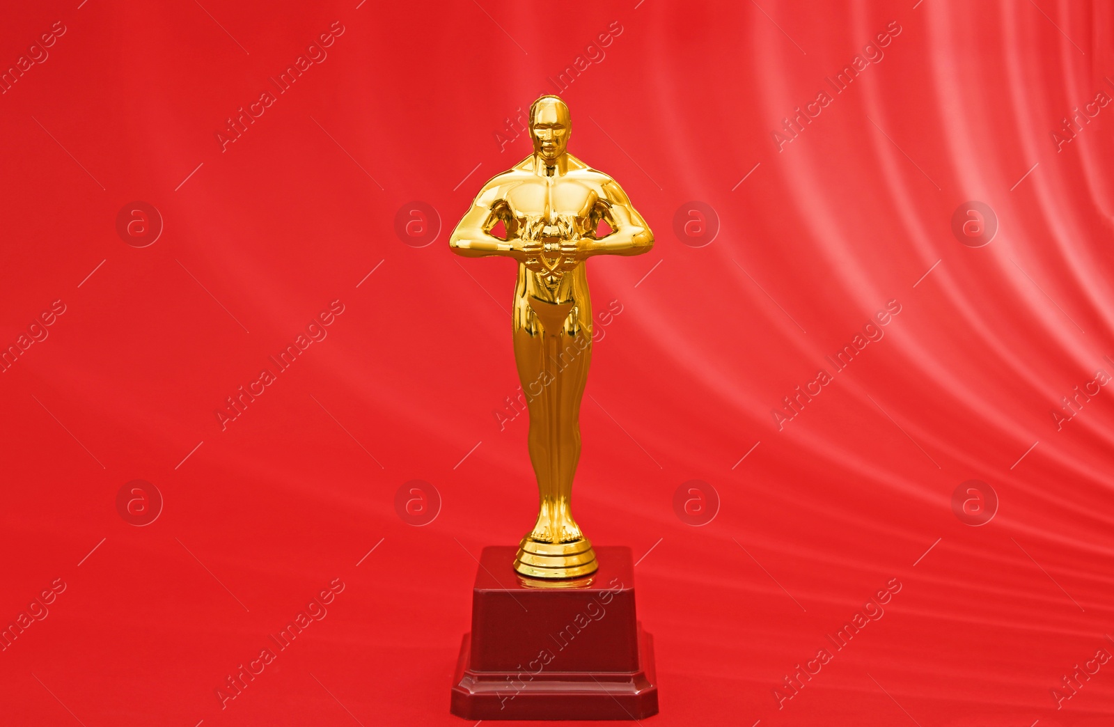 Photo of Golden trophy in shape of human figure on red background