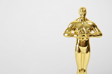 Photo of Golden trophy in shape of human figure d on light background, closeup. Space for text