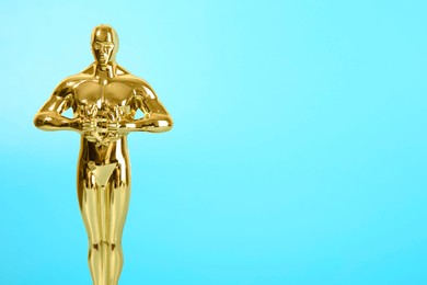 Photo of Golden trophy in shape of human figure on light blue background, space for text