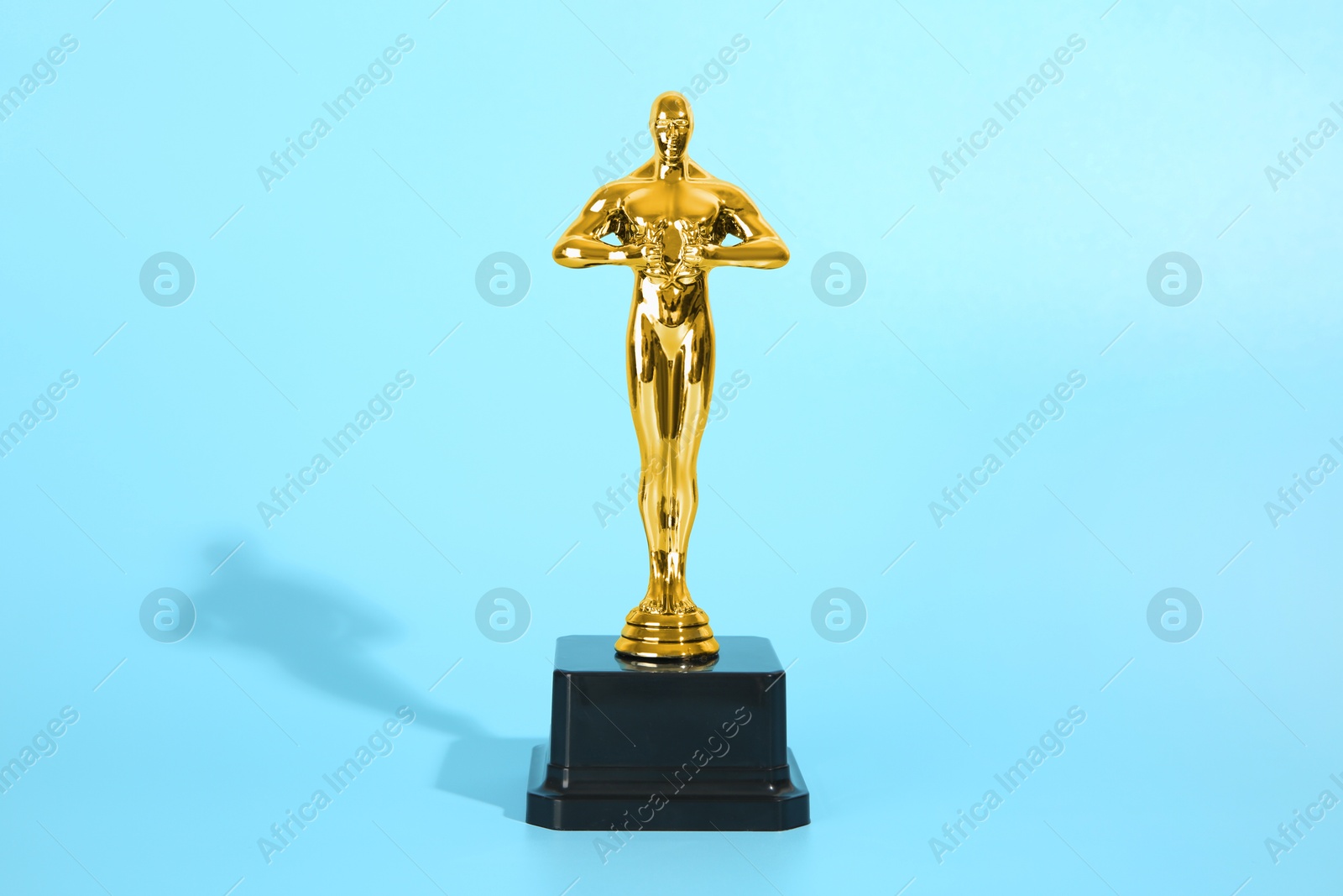 Photo of Golden trophy in shape of human figure on light blue background