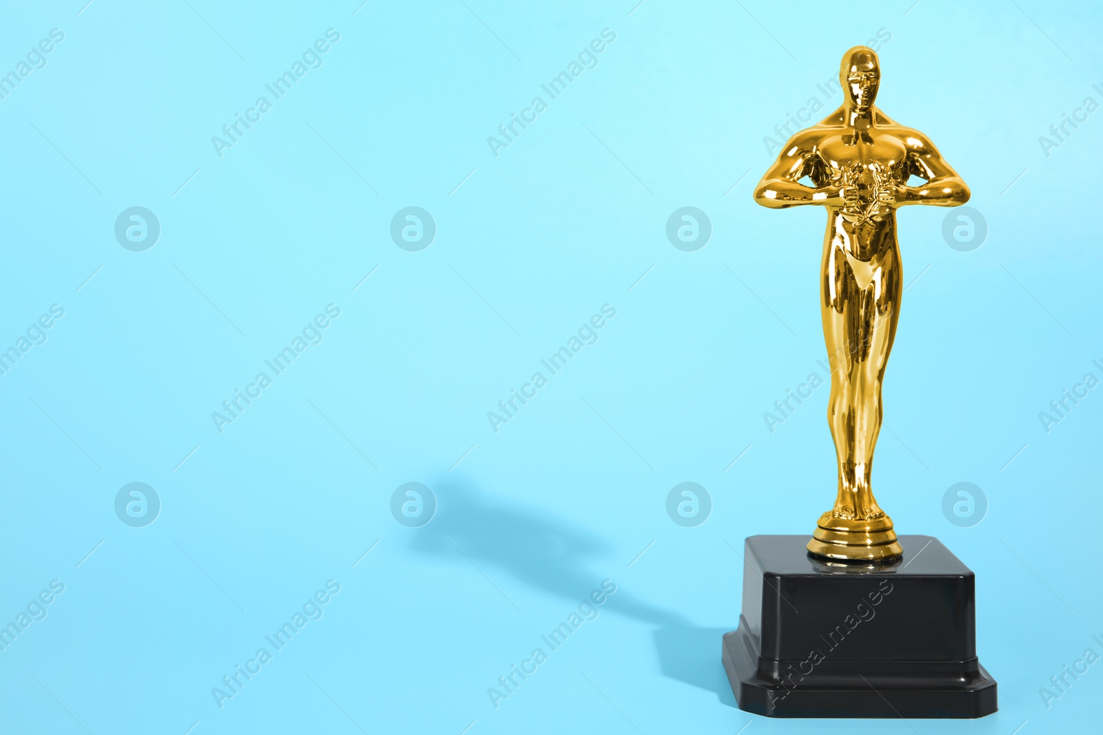 Photo of Golden trophy in shape of human figure on light blue background, space for text