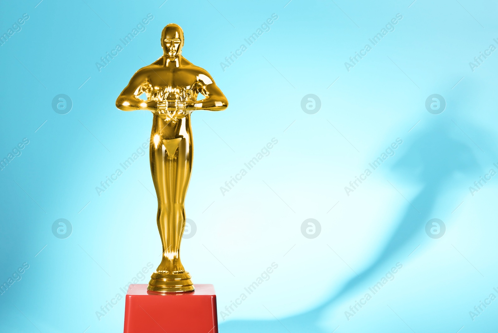 Photo of Golden trophy in shape of human figure on light blue background, space for text