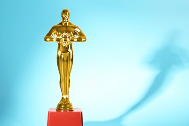 Photo of Golden trophy in shape of human figure on light blue background, space for text