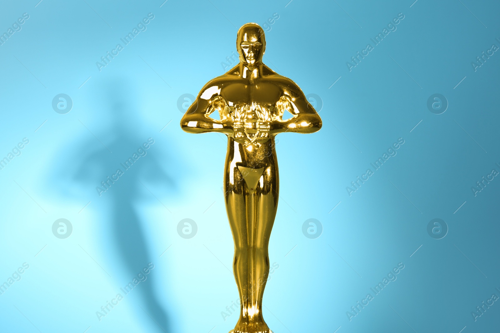 Photo of Golden trophy in shape of human figure on light blue background