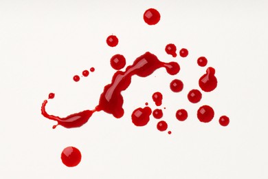 Photo of Drops of blood on white background, top view