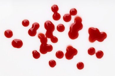 Photo of Drops of blood on white background, top view