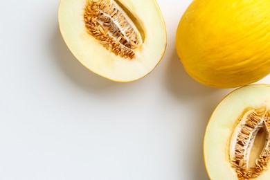 Photo of Fresh whole and cut melons on white background, flat lay. Space for text