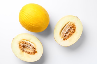 Fresh whole and cut melons on white background, flat lay