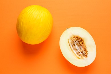 Photo of Whole and half of fresh melon on orange background, flat lay