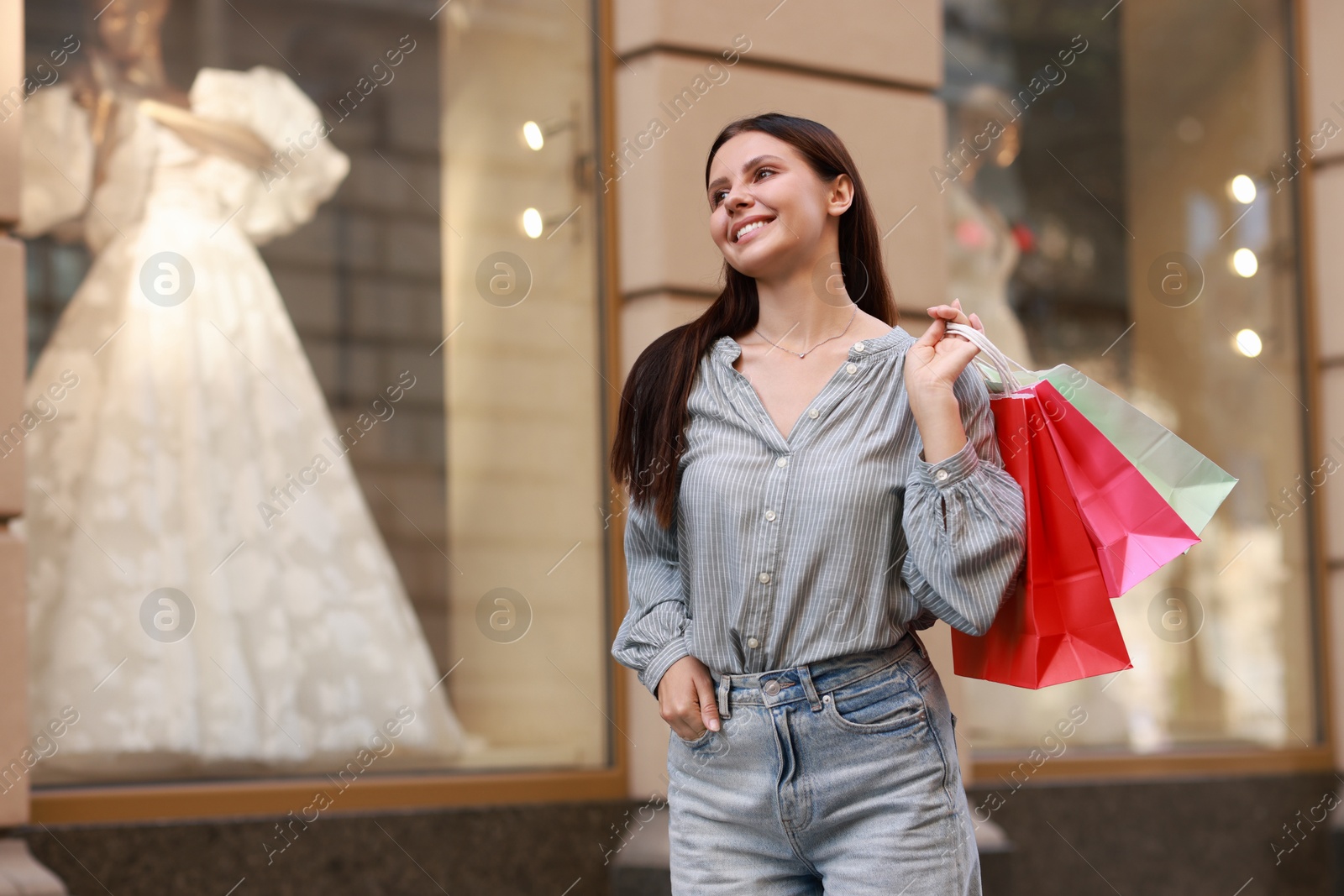 Photo of Happy woman with colorful shopping bags outdoors, space for text