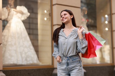 Happy woman with colorful shopping bags outdoors, space for text