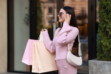 Photo of Happy woman with colorful shopping bags outdoors