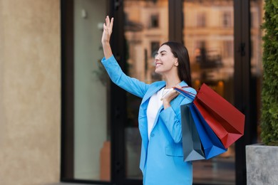 Happy woman with colorful shopping bags outdoors, space for text