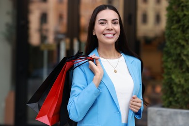 Photo of Happy woman with colorful shopping bags outdoors