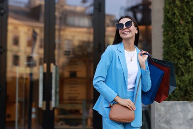 Happy woman with colorful shopping bags outdoors, space for text